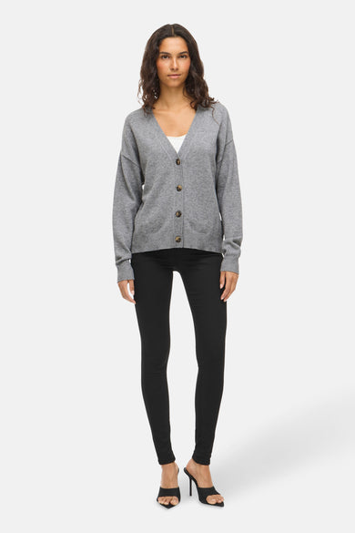 Veste grise de VILA, portée sur un haut blanc et associée à une jupe noire et des bottines.