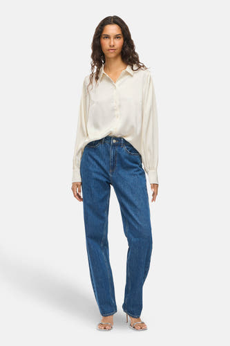 Chemise blanche à manches longues de VILA®, modèle décontracté, associée à des jeans bleus et des talons argentés.