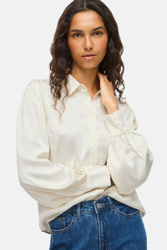 Chemise blanche à manches longues de VILA, avec des poignets à boutons et portée avec un jean.