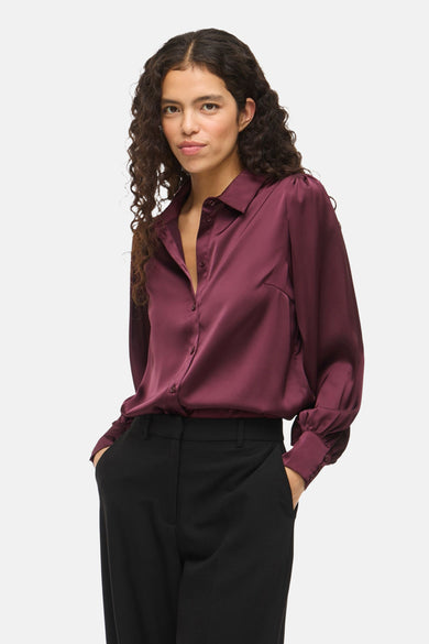 Chemise bordeaux de VILA® avec des manches longues et une finition brillante, associée à un pantalon noir.