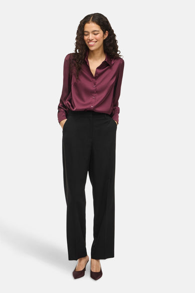 Chemise Bordeaux à manches longues de VILA®, avec col boutonné et portée avec un pantalon noir et des chaussures Bordeaux.