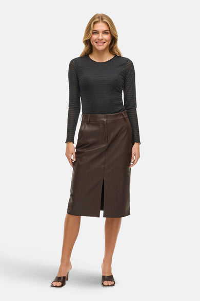T-shirt noir à manches longues de VILA®, porté avec une jupe en cuir marron à fendu et à talons.