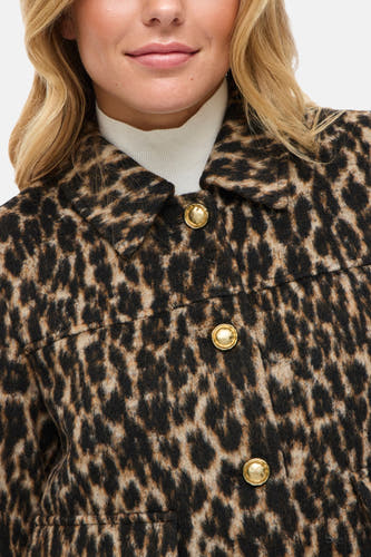 Manteau court brun de Vila, avec imprimé d'animaux et boutons dorés, porté sur une chemise blanche.