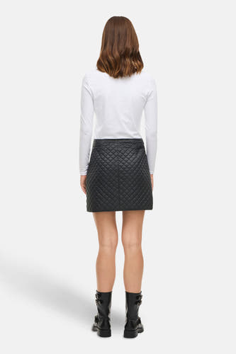 Jupe courte noire de VILA, avec un motif de col en dentelle, associée à une chemise blanche à manches longues et des bottes noires.