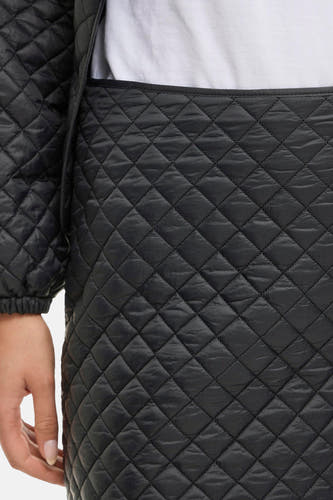 Jupe courte noire de VILA®, avec un motif de visage doublé et une main visible sur le côté, gros plan.