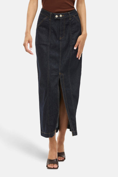 Jupe en denim bleu marine de VILA, avec une fente à l'avant et des sandales brunes.