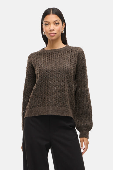 Pull marron avec col rond de VILA, en texture tricotée grossière, associé à un pantalon noir large et des escarpins marrons.