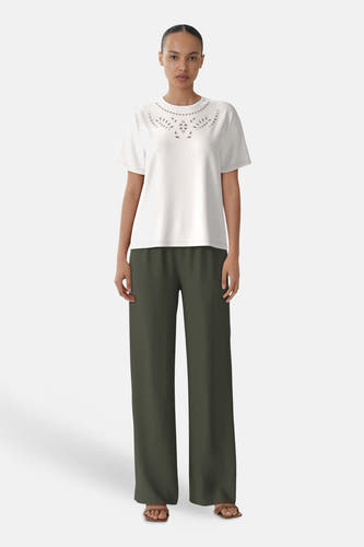 T-shirt blanc à manches courtes de VILA®, avec des découpes décoratives autour de la ligne du col, associé à un pantalon kaki et des sandales.
