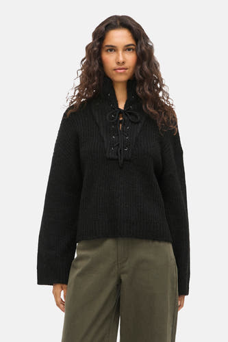 Pull noir de VILA® avec une fermeture à glissière, associé à des pantalons olive et des baskets noires.