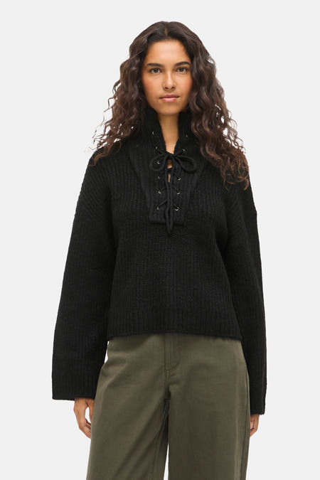 Pull noir de VILA® avec une fermeture à glissière, associé à des pantalons olive et des baskets noires.