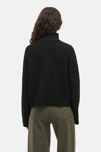 Pull noir de VILA, vu de de lrière avec un col haut et et et texture textureuréeée combiné à des pantalons verts.