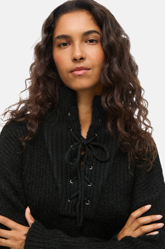 Vrouw in een zwarte gebreide trui met veterdetails.