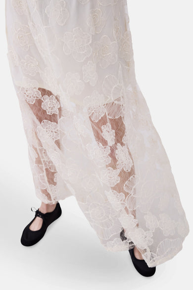 Longue jupe écru de VILA, avec un motif floral et une matière transparente, associée à des chaussures noires.