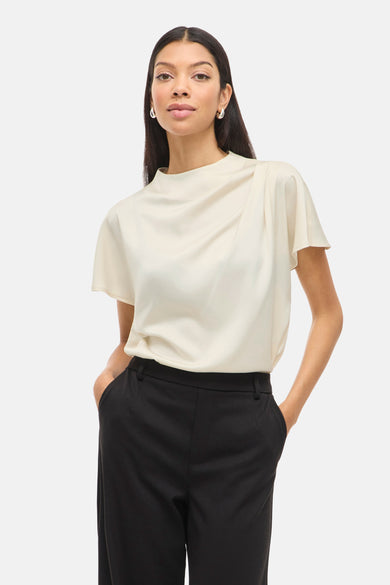 Blouse écru à manches courtes de VILA®, avec col plié et associée à un pantalon noir.