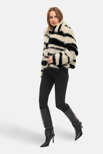 Korte bontjas van VILA® met zebra patroon, gecombineerd met zwarte skinny jeans en leren laarzen met hak.
