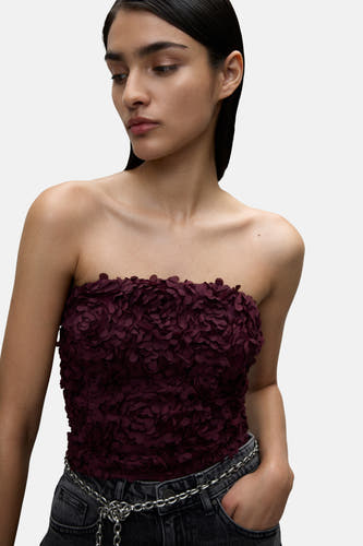 Blouse Bordeaux de VILA® à imprimé floral, associée à un jean gris et une ceinture en chaîne.