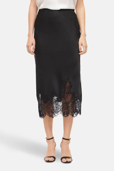 Robe noire de VILA, avec des détails sur les bords en bas et portée avec des sandales noires.