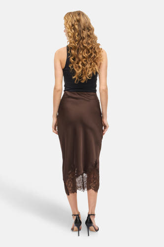 Jupe brune de VILA®, avec des détails sur les bords en bas, portée avec un haut noir et des baskets noires.