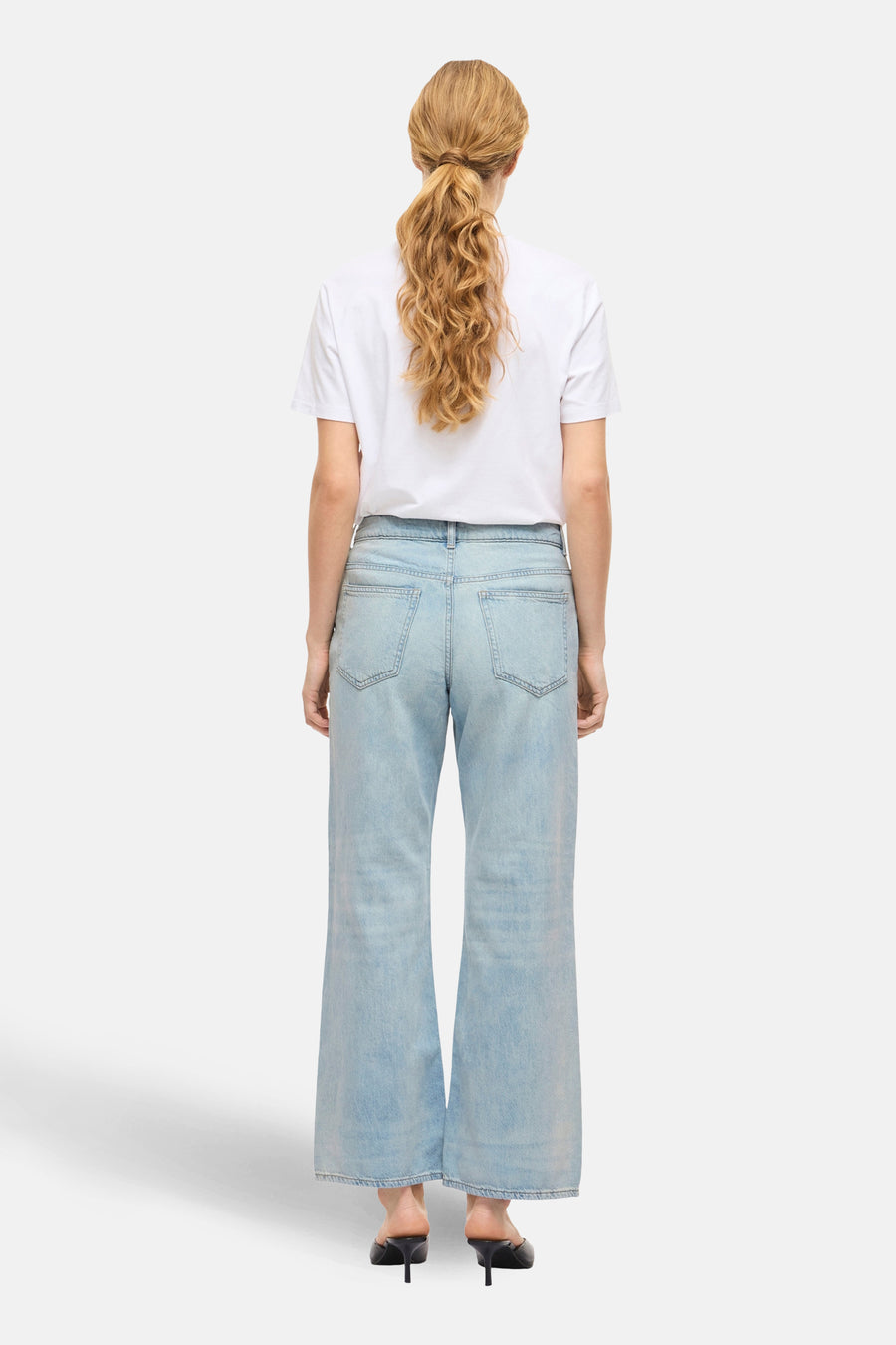 PALMA jeans bleu denim large de VILA, vu de de derrière, avec un T-shirt blanc et des baskets noires.