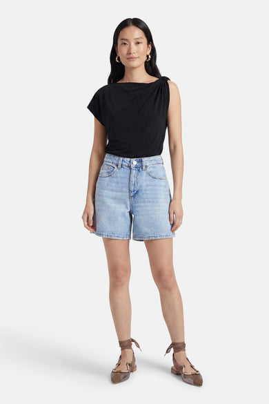 Lichtblauwe denim short van VILA® met hoge taille en voorzakken, gecombineerd met een zwart topje en platte schoenen.