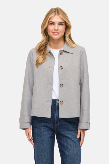 Manteau court gris de VILA®, porté avec un T-shirt blanc et des jeans foncés avec des baskets brunes.