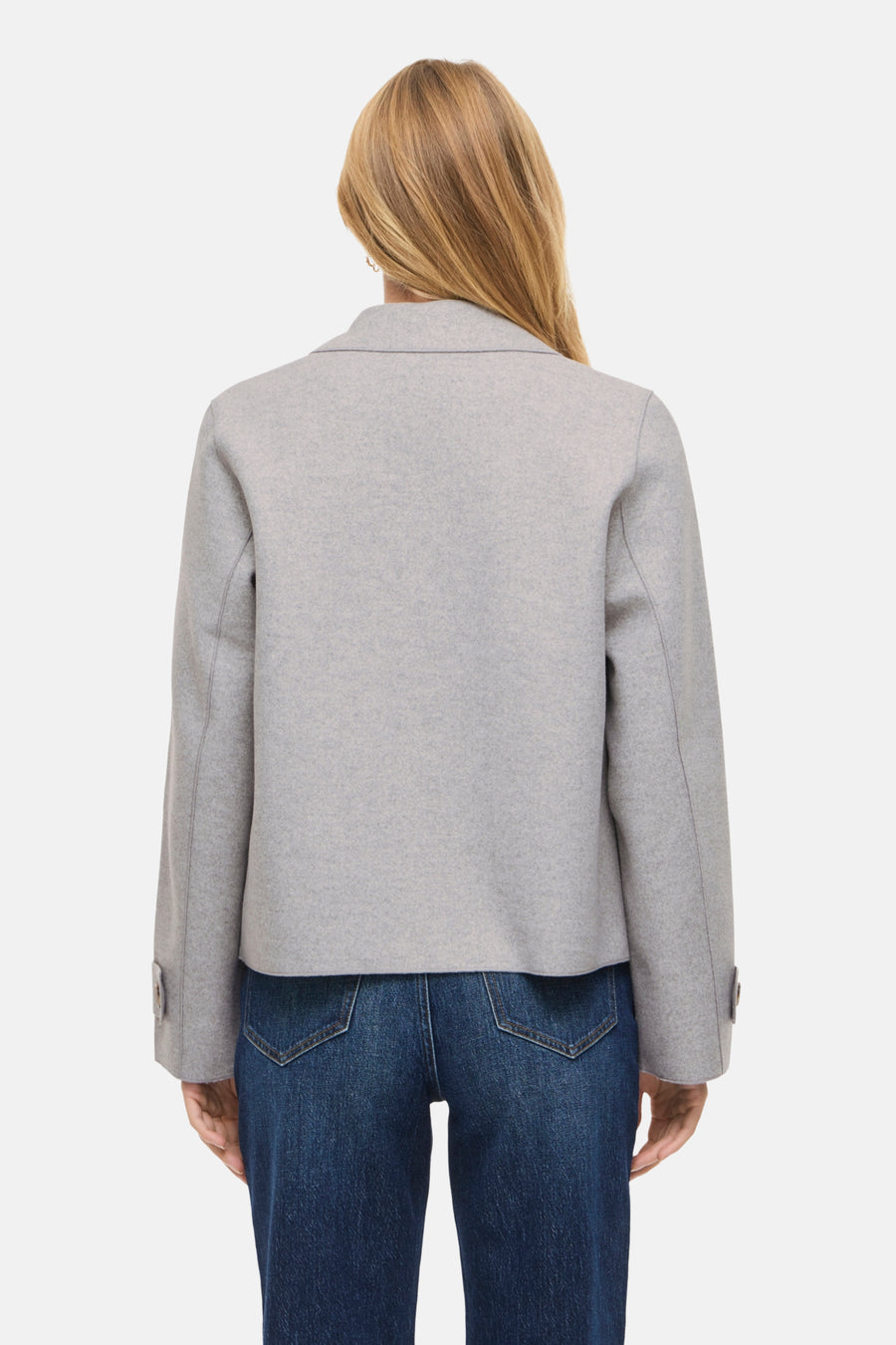 Grijs jasje met blauwe jeans, achteraanzicht.