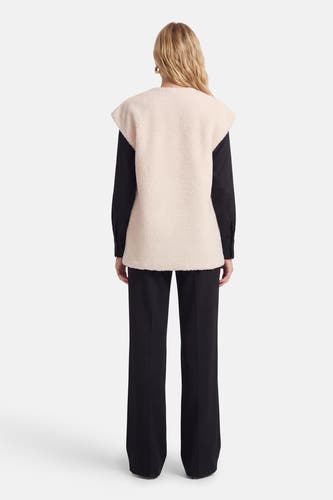 Manteau beige de VILA®, avec une texture douce, porté sur un chemisier et un pantalon noirs, vue de dos.