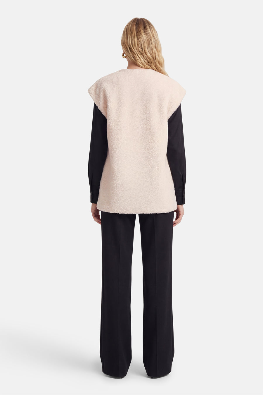 Manteau beige de VILA®, avec une texture douce, porté sur un chemisier et un pantalon noirs, vue de dos.