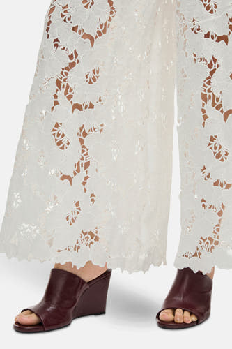 Pantalon blanc de VILA®, avec un motif floral sur les bords, associé à des bottes marron avec une semelle compensée.