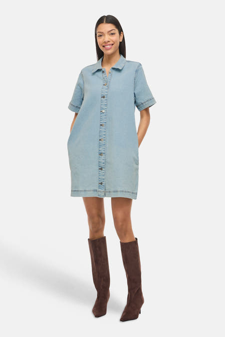 Robe en jean bleu clair à manches courtes de VILA®, avec boutons sur le devant et bottes marron.