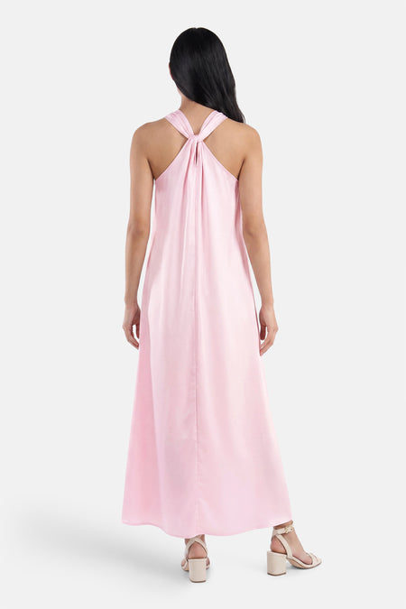 Robe longue rose de VILA® avec bretelles nouées au dos, portée par un mannequin avec des sandales beiges.