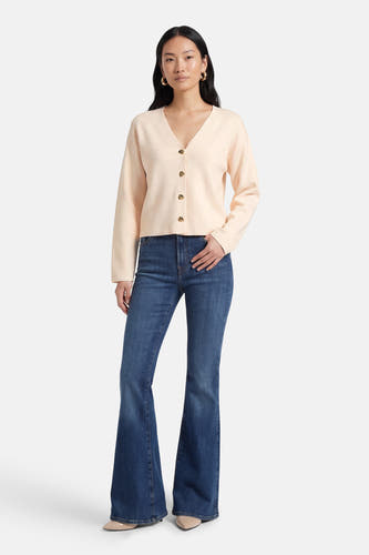 Gilet écru de VILA®, à manches longues et boutons dorés, combiné avec un jean bleu à jambes évasées.