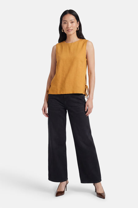 Mouwloze gele blouse van VILA® met zijsplitten en strikjes, gecombineerd met zwarte broek en bruine pumps.