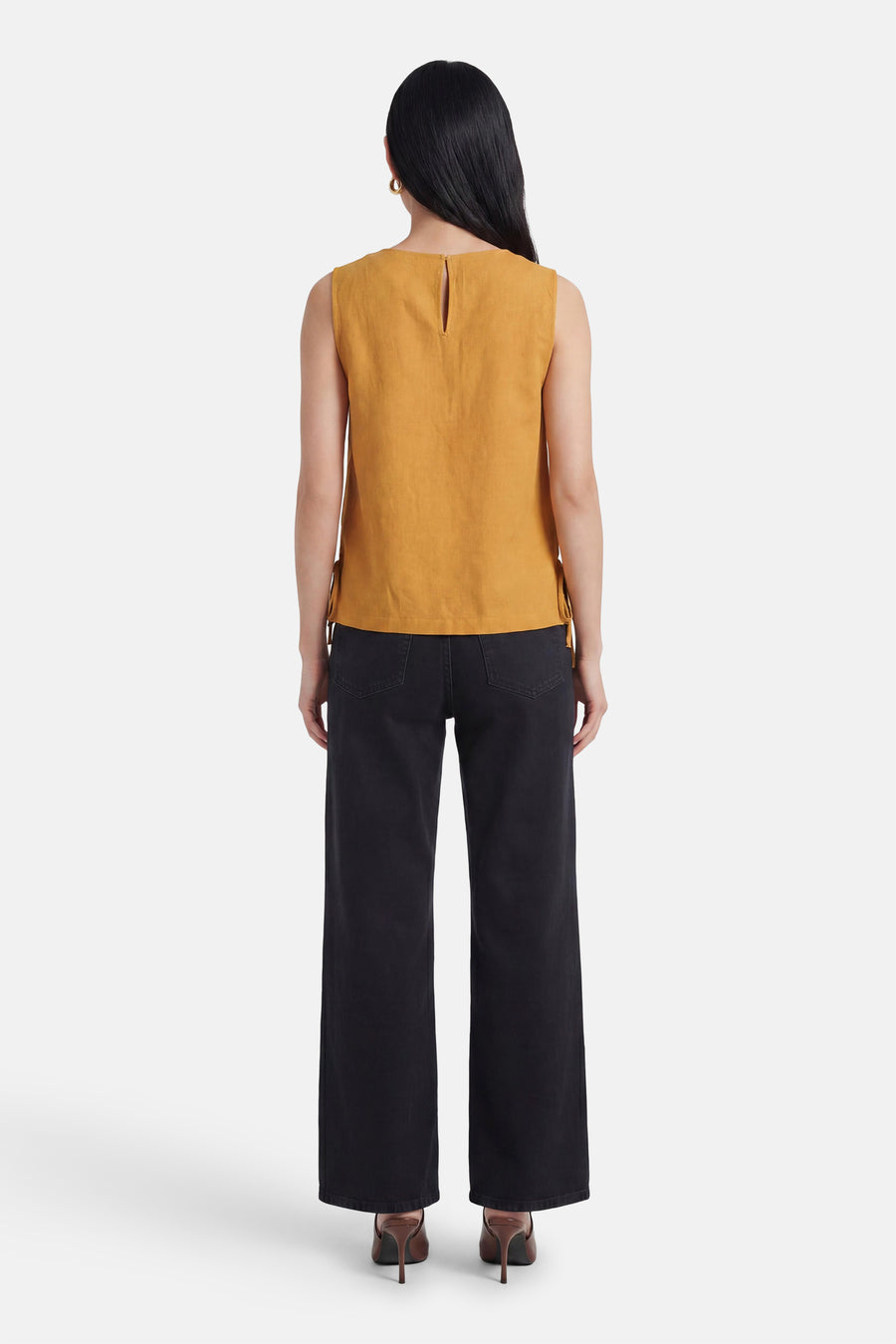 Dos de chemisier sans manches jaune de VILA® avec découpe en trou de serrure au niveau du cou et nœuds sur les côtés, porté avec un jean noir et des talons.