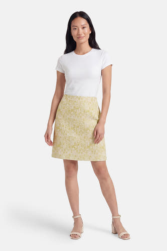 Jupe courte verte de VILA® avec un motif floral subtil, portée par un mannequin avec un t-shirt blanc et des sandales.