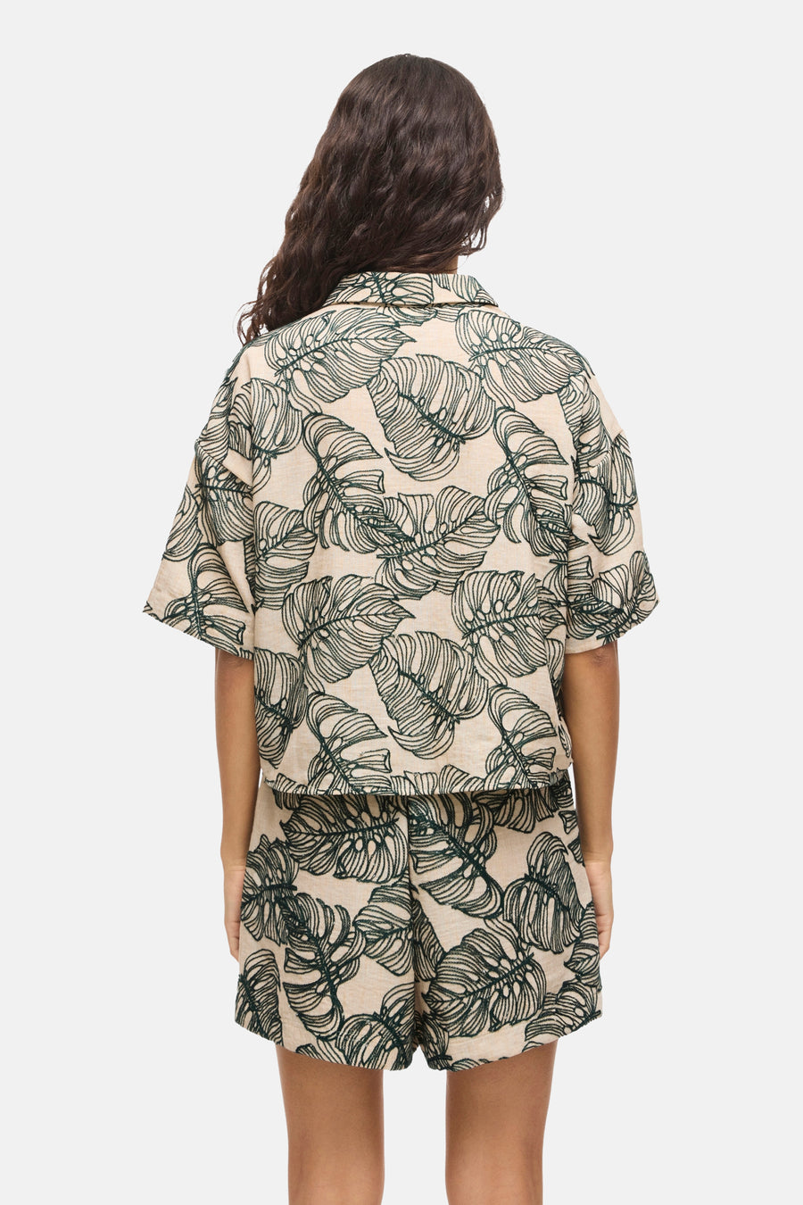 Chemise beige clair à manches courtes avec motif de feuilles vertes de VILA®, vue de dos, portée avec un short assorti.