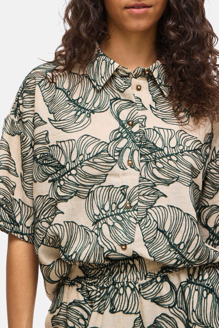 Chemise à manches courtes VILA® de couleur beige avec un motif de feuilles vertes détaillé et une fermeture à boutons.