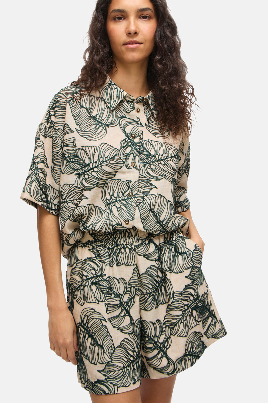 Chemise courte à manches courtes de couleur claire avec motif de feuilles structurées vertes de VILA®, avec boutons dorés et short assorti.