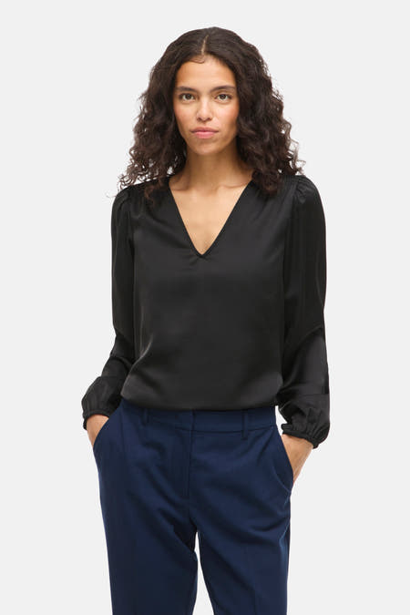 Blouse noire à manches longues de VILA, avec un col en V et des manches drapées.