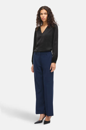 Blouse noire à longues manches de VILA®, portée avec un pantalon bleu et des bottes noires.