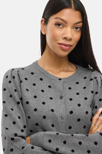 Vrouw met grijze vest met zwarte stippen.
