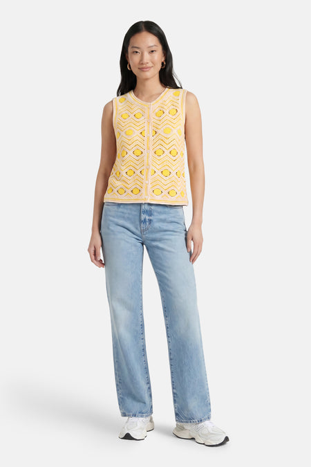 Gele gebreide gilet met geometrisch patroon van VILA®, gedragen met lichtblauwe jeans en witte sneakers, front view