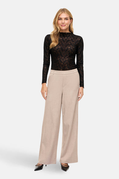 Zwarte longsleeve van VILA, met bloemenkant details. Gedragen met beige pantalon en zwarte hakken.