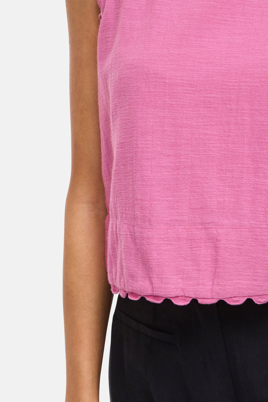 Chemisier sans manches rose de VILA® avec une texture tissée, un ourlet festonné et une taille froncée, porté avec un pantalon noir.