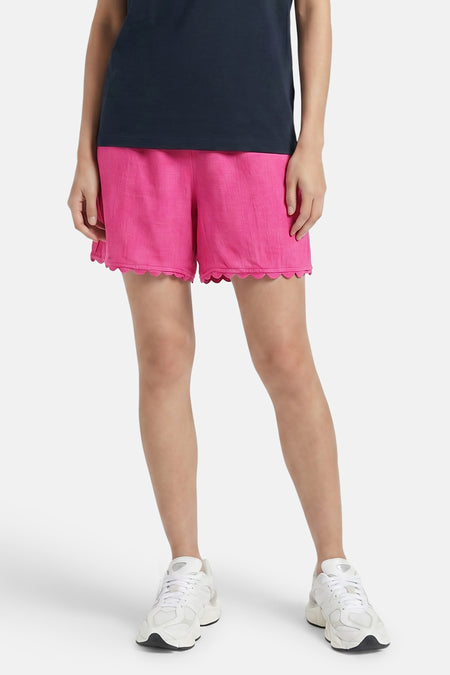 Roze korte broek van VILA® met geborduurde zoom, gedragen met donkerblauw tanktop en witte sneakers, front view