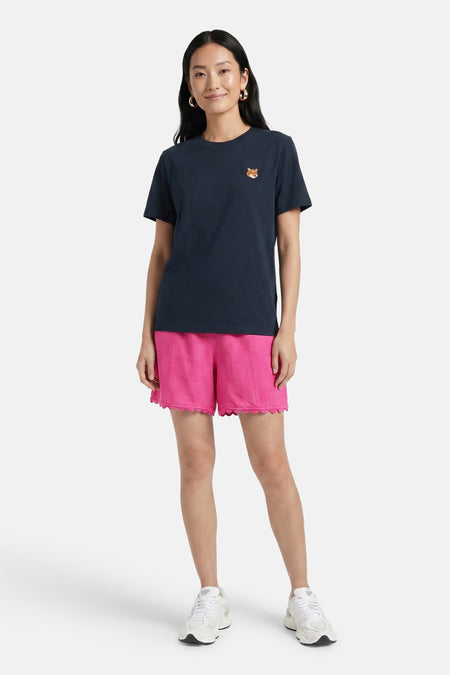 Roze korte broek van VILA® met geborduurde zoom, gedragen met donkerblauw T-shirt en witte sneakers, front view