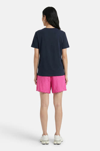 Roze korte broek van VILA® met geborduurde zoom, gedragen met donkerblauw T-shirt en witte sneakers, achterkant weergegeven