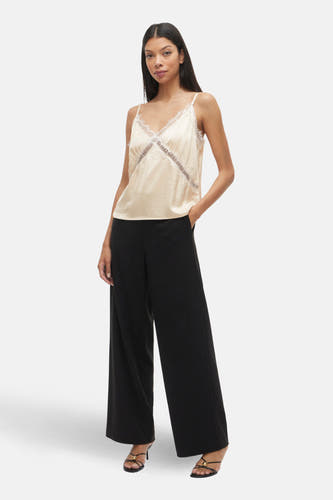 Ecru blouse zonder mouwen van VILA, met kanten details, gecombineerd met zwarte, wijde broek en sandalen met hak.
