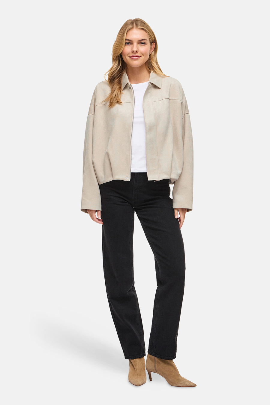 Beige korte jas van VILA®, met lange mouwen en gedragen over een wit shirt en een zwarte jeans.
