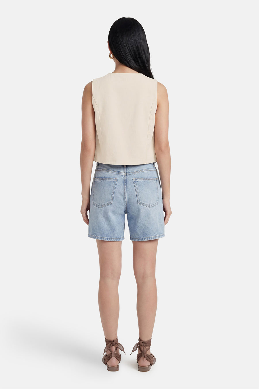 Beige mouwloos gilet van VILA, kort gesneden, gedragen op een denim short met bruine sandalen.